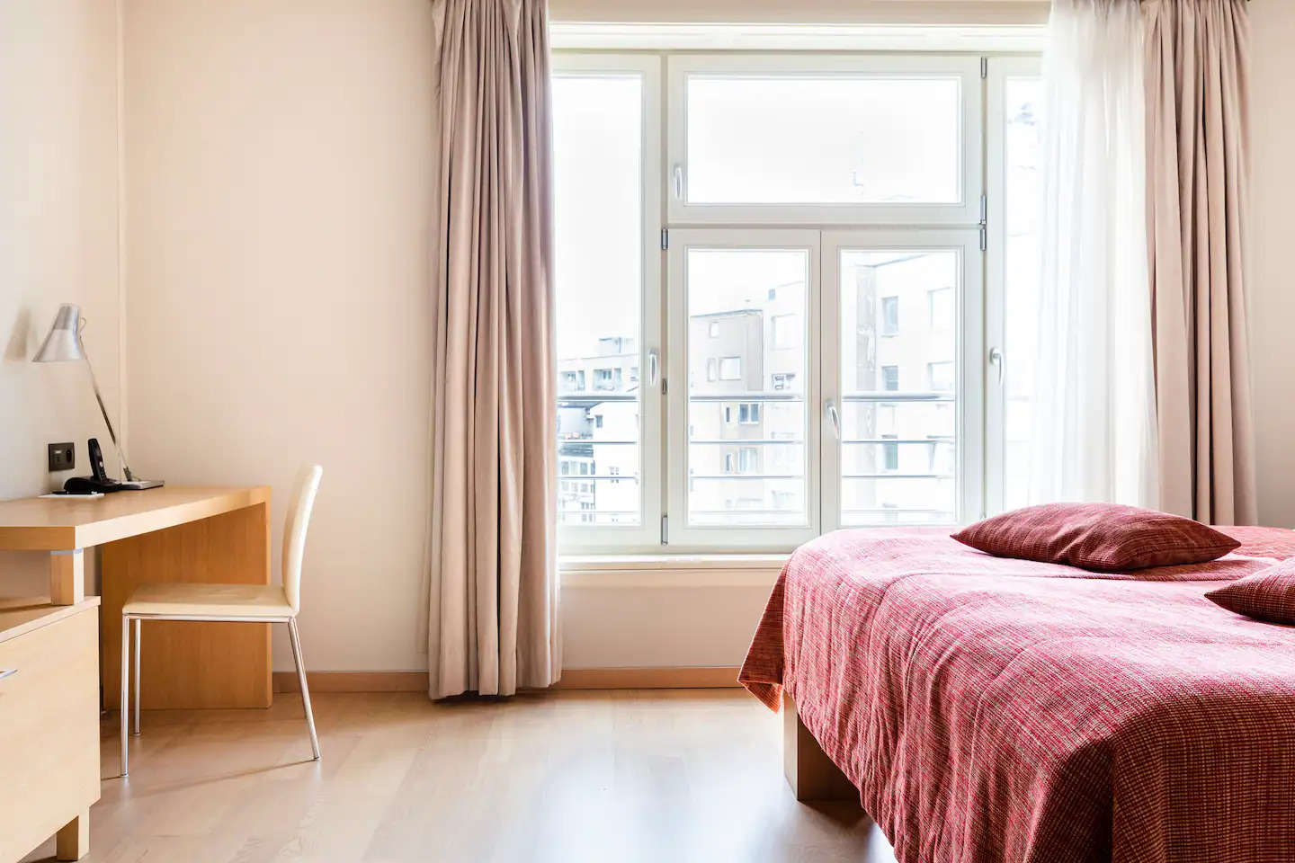 Bedroom with tall window and morning light over Bratislava